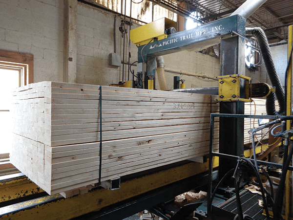 A stack of lumber moves through a Pacific Trail Mfg. cross-cut machine.